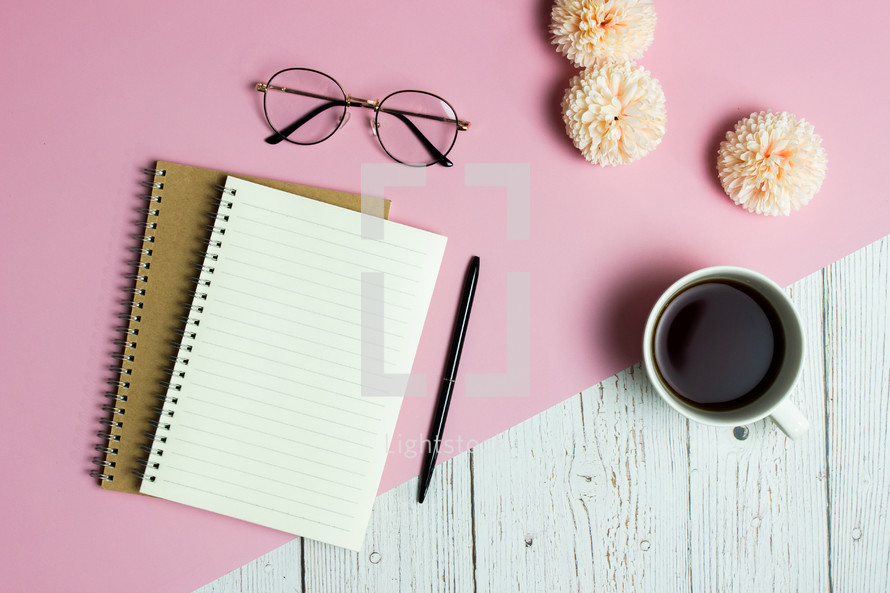 Sweet writing items with pink roses, coffee cup and glasses over pink background. 