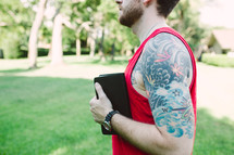 man with tattoos holding a Bible 