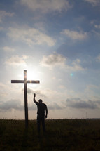 a man praying in front of a cross with a raised hand 