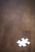 white puzzle piece on a wood table