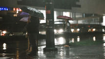 people with umbrellas standing in the rain at night 