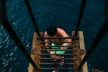 a man climbing up a ladder out of a lake 