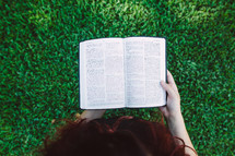 woman reading a Bible in the grass 