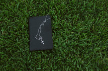 Bible and cross necklace in the grass 