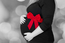 Woman's hands embracing her pregnant stomach.