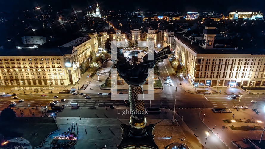 Kyiv, Ukraine - April, 2023: Maidan Nezalezhnosti square at night - aerial drone view. Monument of Independence - Berehynia in the center. Golden beautiful Ukrainian woman statue.
