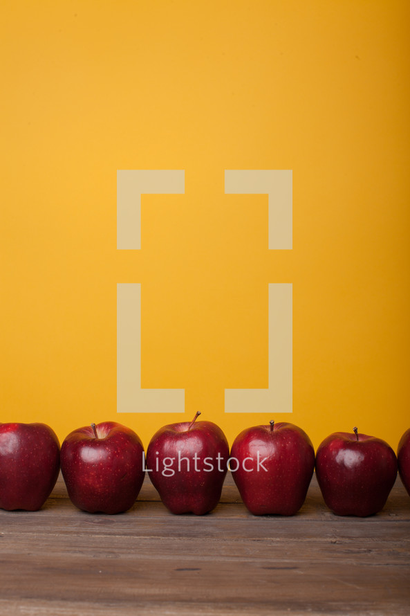 a row of apples on a desk 