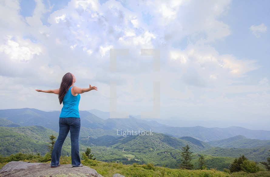 woman standing standing on a rock with outstretched arms 