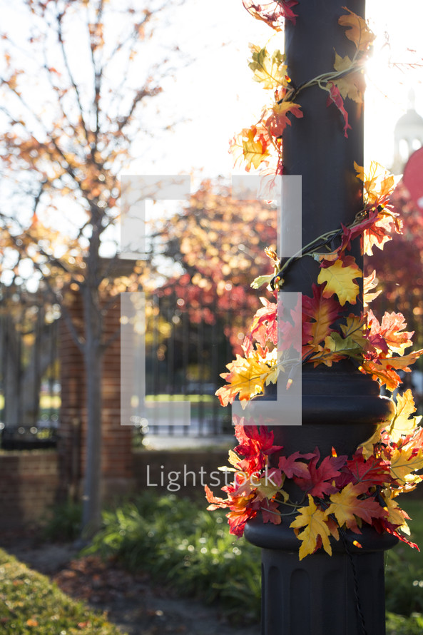 decorative fall leaves around an outdoor lamp post 