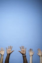 raised hands against a blue sky 