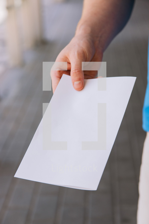 Close up of a man holding out a blank flyer.