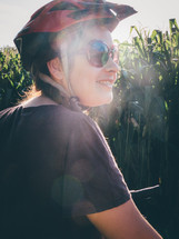 woman in a bike helmet in front of a corn field 
