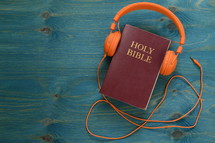 bible with orange headphones on teal wooden background