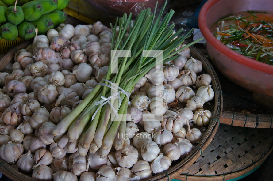 Green onions in a basket of garden cloves. Bananas in the background.