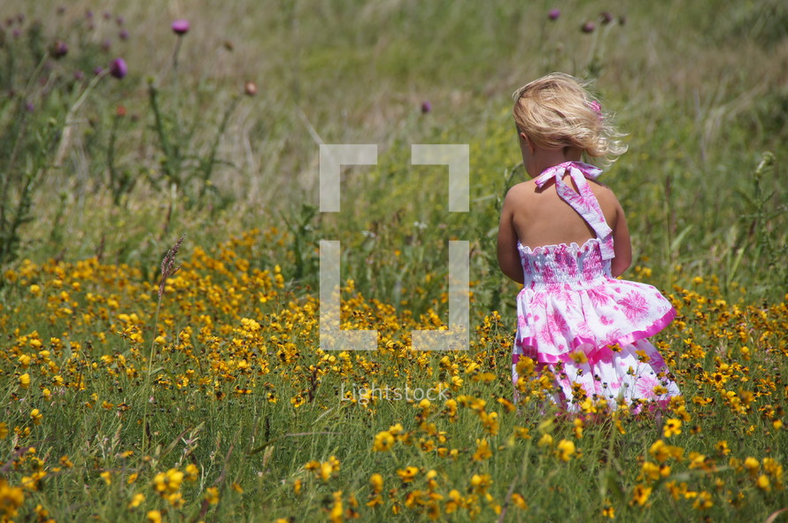 Young girl standing in field with flowers