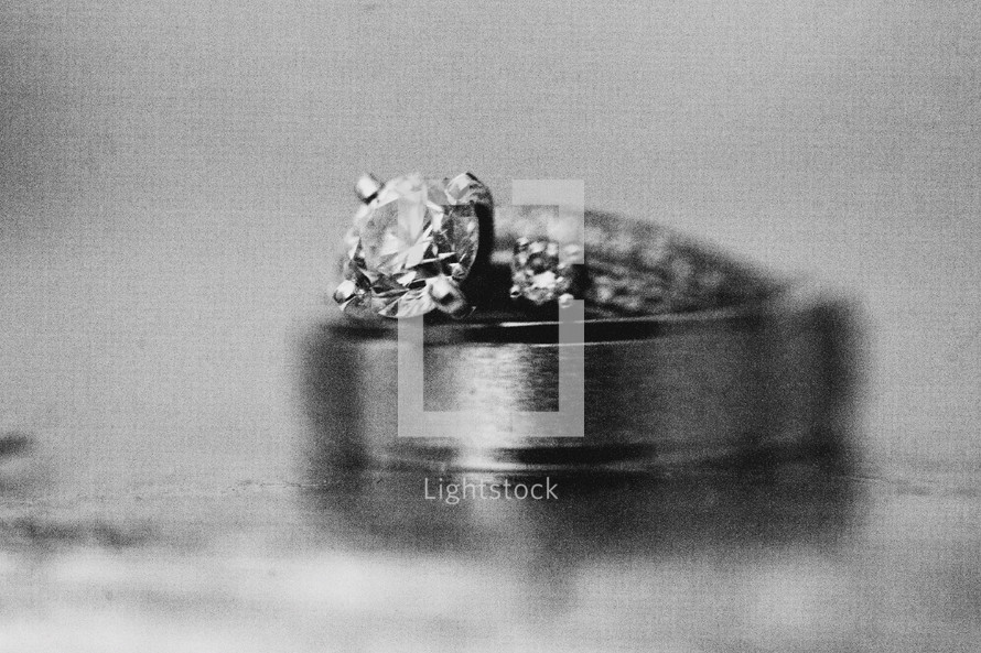 Engagement ring and wedding band sittng on top of solid surface.
