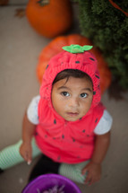 a toddler in a strawberry costume 