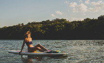 woman sitting on a paddle board 