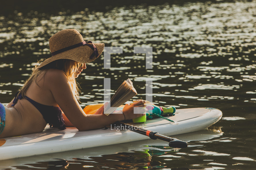 woman reading lying on a paddle board 