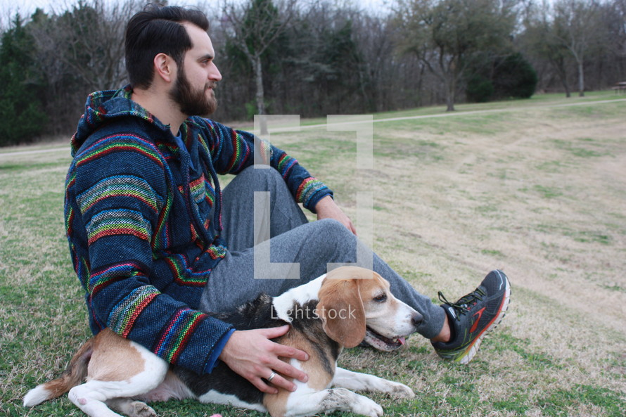 a man sitting with his beagle dog