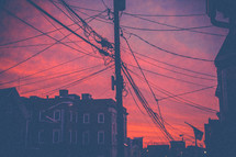 power lines and glow of a pink sky in a city 