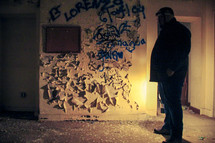 a man standing in an abandoned building covered in graffiti 