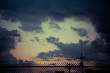 chain link fence and clouds in the sky at sunset 