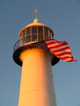 top of a lighthouse, with an American flag blowing in the wind