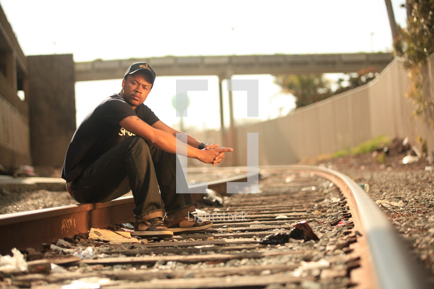 man sitting on railroad tracks