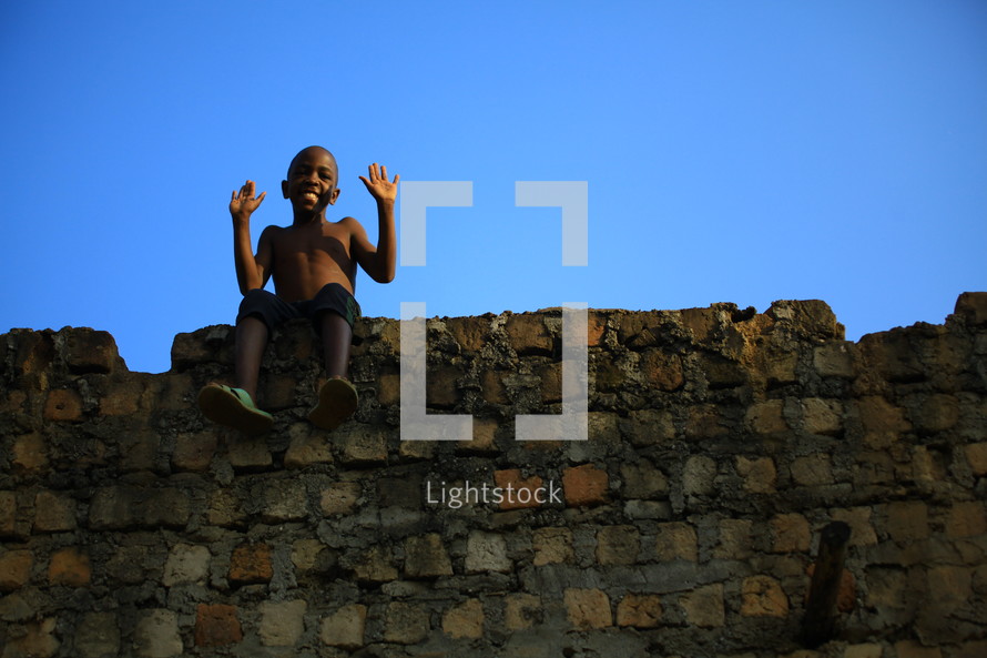 African boy sitting on stone wall