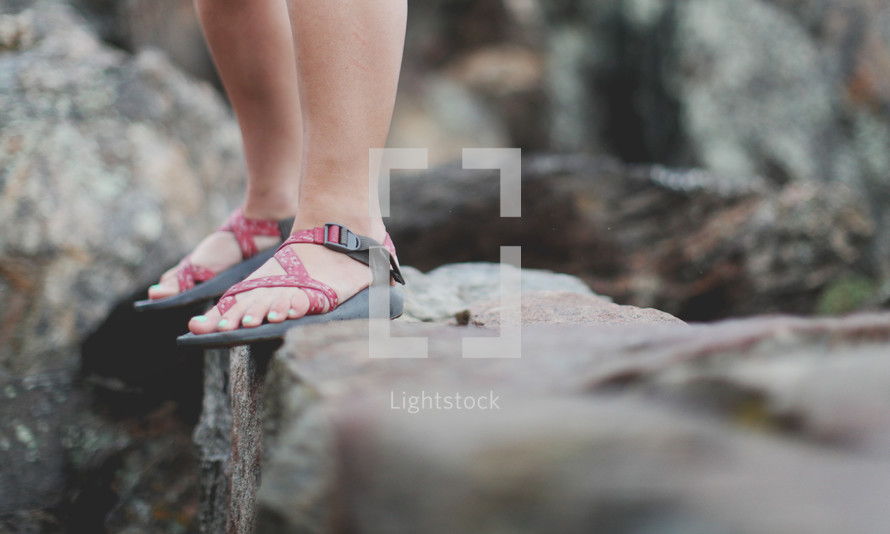 standing in sandals on a rocky ledge