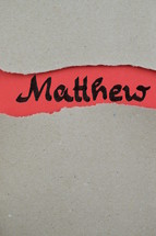Matthew - torn open kraft paper over light red paper with the name of the Gospel of Matthew