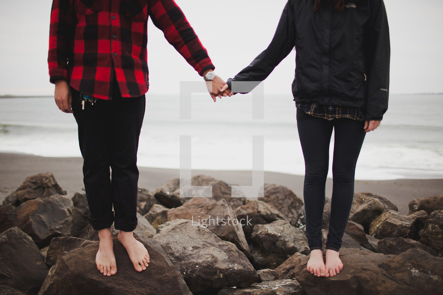 A couple standing on rocks holding hands