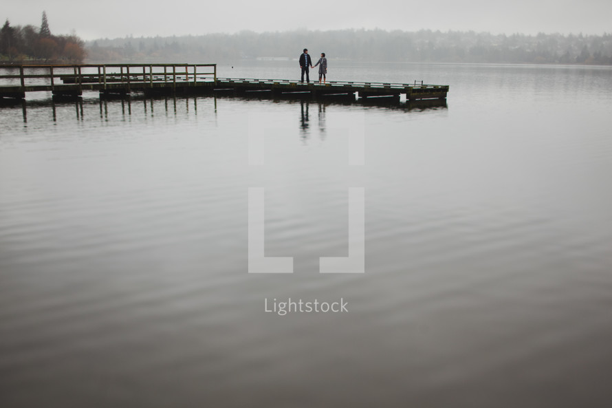 man and woman standing on a dock holding hands