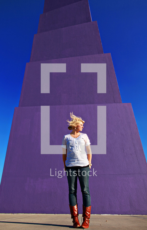 A young woman stands in front of a purple statue