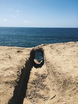 worn hole in rock near the ocean 