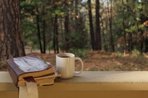 Bible and coffee mug on a railing outdoors 