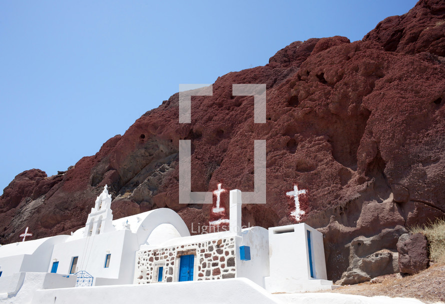 Traditional chapel with Greece flag in red beach, Santorini