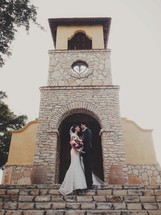 bride and groom kissing in front of a church 