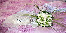 Bridal bouquet with shoes and garter on the wisteria bed.