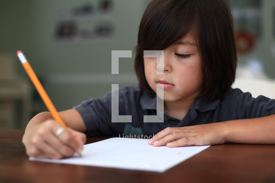 Boy writing on paper with pencil