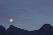 The moon rising over a mountain.