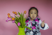 girl child with colorful tulips in a vase 