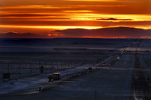 Snow blowing across interstate at sunset.