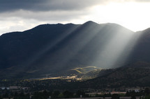 rays of sunlight shining on a valley below 