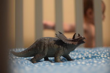 a dinosaur toy in a crib and infant 