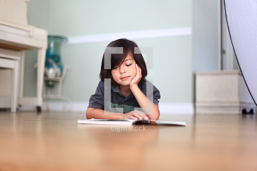 young boy lying on the floor reading