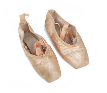Old used pink ballet shoes on white background