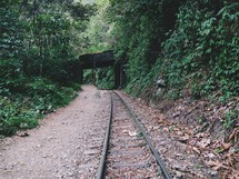 A railroad track leading under an old bridge.