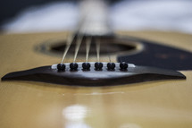 Close-up of a bridge and strings of an acoustical guitar.